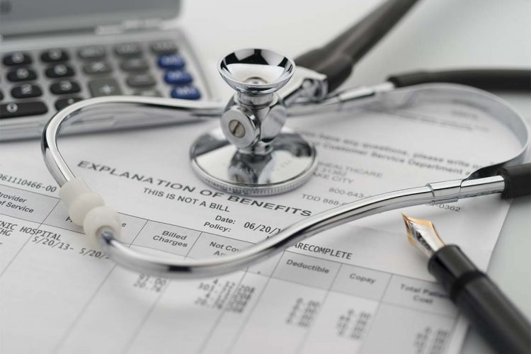 Figuring cost of health care and benefits with stethoscope and calculator in background