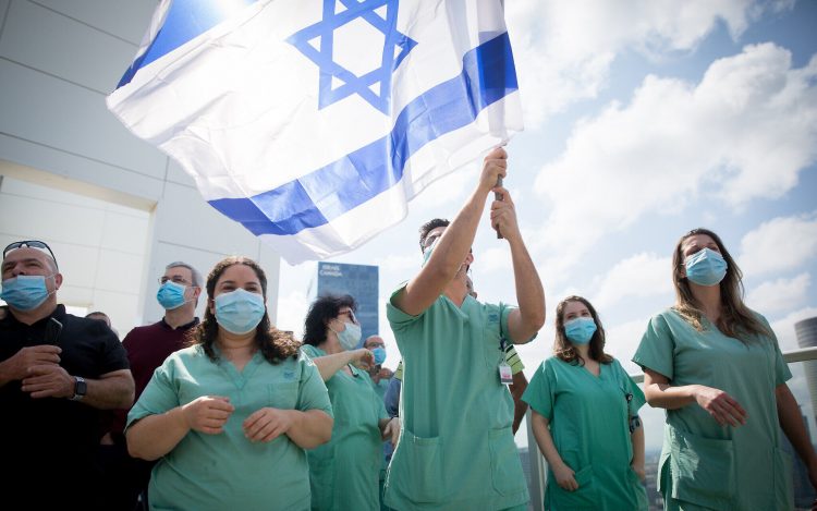 Israeli medical staff cheer an Israeli airforce acrobatic team flying over Ichilov hospital in Tel Aviv on Israel's 72nd Inependence Day. This year, the airforce will fly over all the hospitals in Israel as a way of honouring the medical staff during the Coronavirus outbreak. April 29, 2020. Photo by Miriam Alster/Flash90 *** Local Caption *** יום העצמאות
מטס
תל אביב
איכילוב
קורונה
מטוסים
תל אביב
דגלים
דגל ישראל