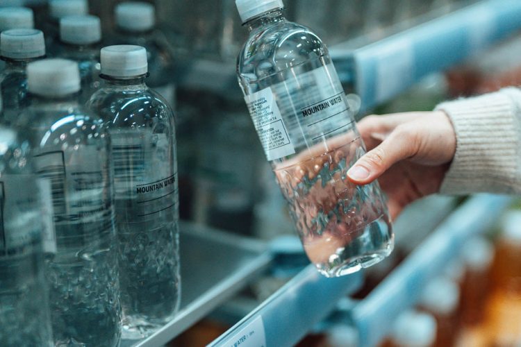Close up shot of a woman buying bottled water in supermarket. BPA Free concept.
