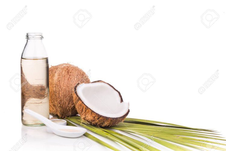 Cold pressed extra virgin coconut oil in bottles with coconut fruits in white background