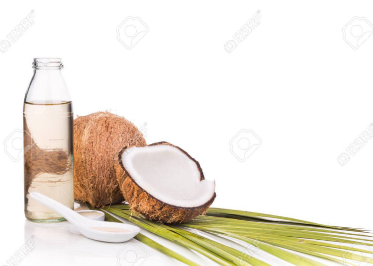 Cold pressed extra virgin coconut oil in bottles with coconut fruits in white background