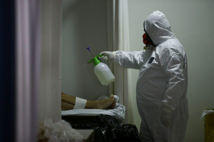 SENSITIVE MATERIAL. THIS IMAGE MAY OFFEND OR DISTURB    A worker of a funeral parlour, sanitises the dead body of an 83-years-old woman, who died of unknown reasons during the outbreak of the coronavirus disease (COVID-19), in Porto Alegre, Brazil, April 3, 2020. REUTERS/Diego Vara