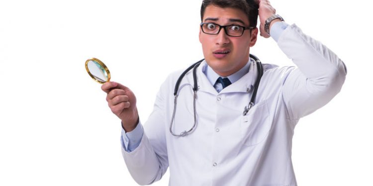 84496572 - young male doctor with a looking magnifying glass isolated on white background