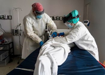 HOUSTON, TX - JUNE 30: (EDITORIAL USE ONLY)  Medical staff wears full PPE as they wrap a deceased patient with bed sheets and a body bag in the Covid-19 intensive care unit at the United Memorial Medical Center on June 30, 2020 in Houston, Texas. Covid-19 cases and hospitalizations have spiked since Texas reopened, pushing intensive-care wards to full capacity and sparking concerns about a surge in fatalities as the virus spreads. (Photo by Go Nakamura/Getty Images)
