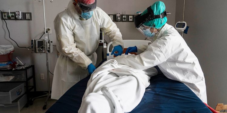 HOUSTON, TX - JUNE 30: (EDITORIAL USE ONLY)  Medical staff wears full PPE as they wrap a deceased patient with bed sheets and a body bag in the Covid-19 intensive care unit at the United Memorial Medical Center on June 30, 2020 in Houston, Texas. Covid-19 cases and hospitalizations have spiked since Texas reopened, pushing intensive-care wards to full capacity and sparking concerns about a surge in fatalities as the virus spreads. (Photo by Go Nakamura/Getty Images)