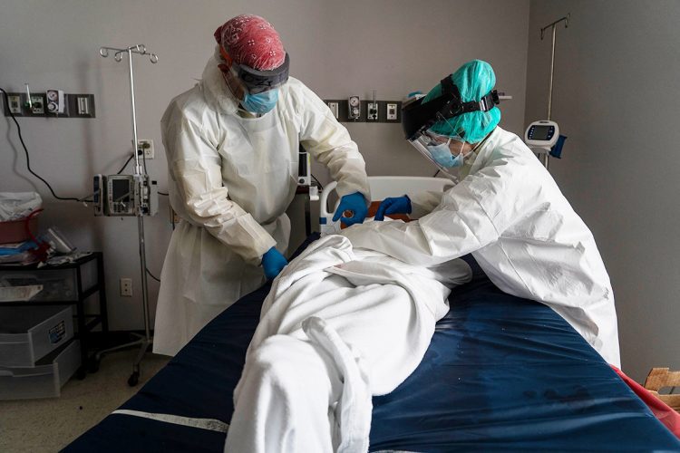 HOUSTON, TX - JUNE 30: (EDITORIAL USE ONLY)  Medical staff wears full PPE as they wrap a deceased patient with bed sheets and a body bag in the Covid-19 intensive care unit at the United Memorial Medical Center on June 30, 2020 in Houston, Texas. Covid-19 cases and hospitalizations have spiked since Texas reopened, pushing intensive-care wards to full capacity and sparking concerns about a surge in fatalities as the virus spreads. (Photo by Go Nakamura/Getty Images)