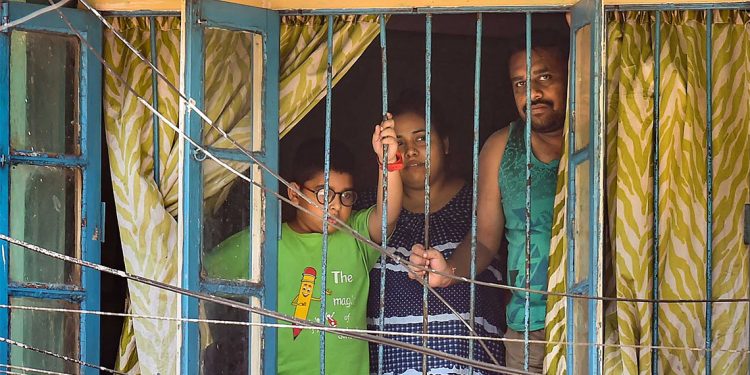 Kolkata: A family looks from the window of a house during the nationwide lockdown imposed to contain the coronavirus pandemic, in Kolkata, Tuesday, March 31, 2020. (PTI Photo/Swapan Mahapatra) (PTI31-03-2020_000112B)