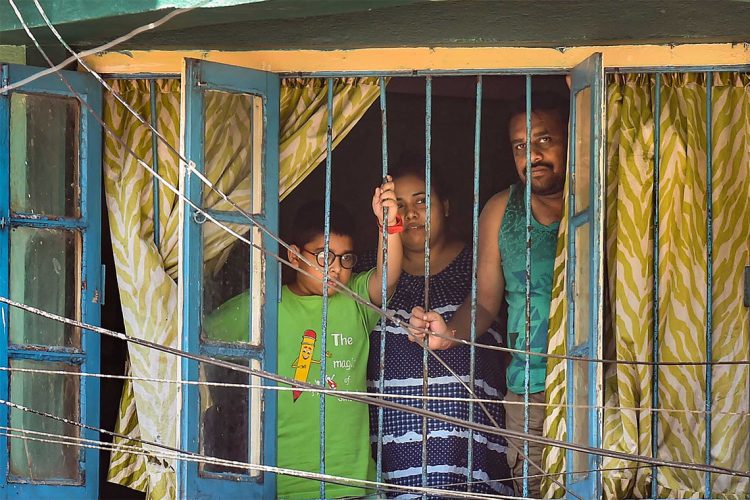 Kolkata: A family looks from the window of a house during the nationwide lockdown imposed to contain the coronavirus pandemic, in Kolkata, Tuesday, March 31, 2020. (PTI Photo/Swapan Mahapatra) (PTI31-03-2020_000112B)