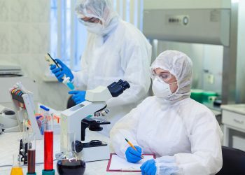 Scientists in protective suits in a science laboratory study a dangerous virus to eliminate the epidemic