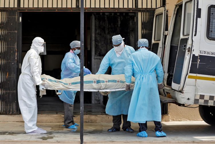 Municipal workers in protective gear carry the body a woman who died due to coronavirus disease (COVID-19), for her cremation at a crematorium in Ahmedabad, India, April 17, 2020. REUTERS/Amit Dave