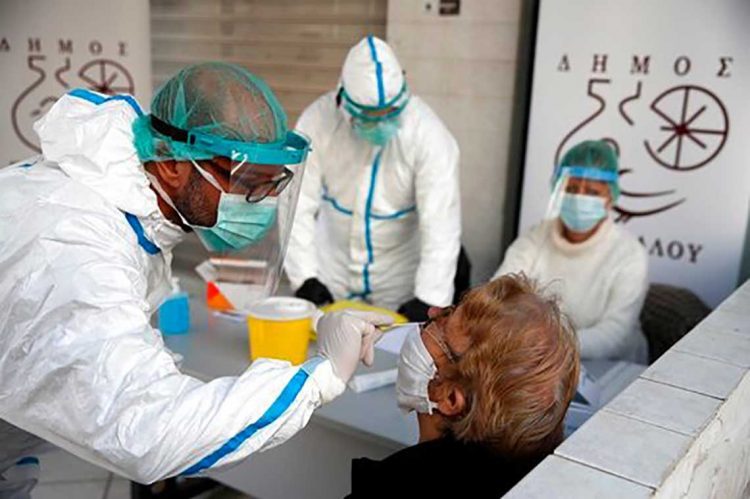 Medical staff conducts a rapid COVID test on an elderly woman in Athens, Monday, Nov. 23, 2020. Greece has seen a major resurgence of the virus after the summer, leading to dozens of deaths each day and thousands of new infections. (AP Photo/Thanassis Stavrakis)