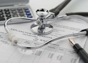 Figuring cost of health care and benefits with stethoscope and calculator in background