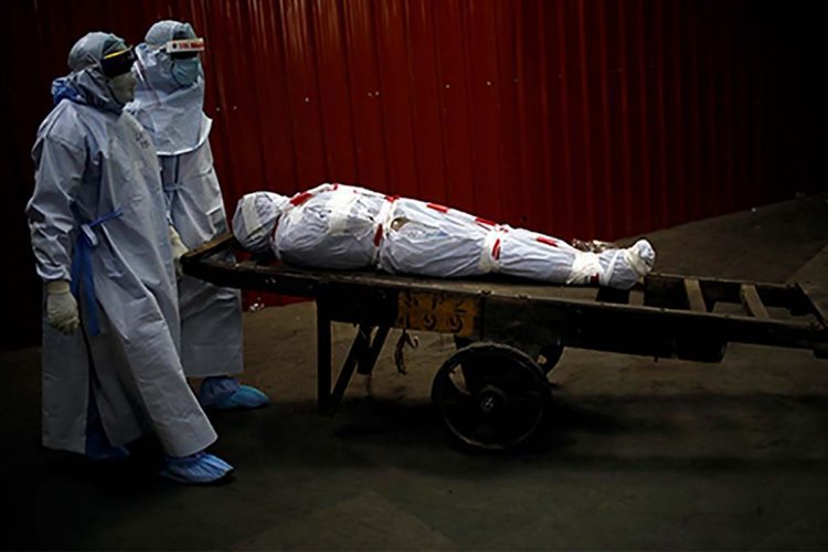 Health workers carry the body of a man who died due to the coronavirus disease (COVID-19) for his cremation at a crematorium in New Delhi, India, June 4, 2020. REUTERS/Adnan Abidi
