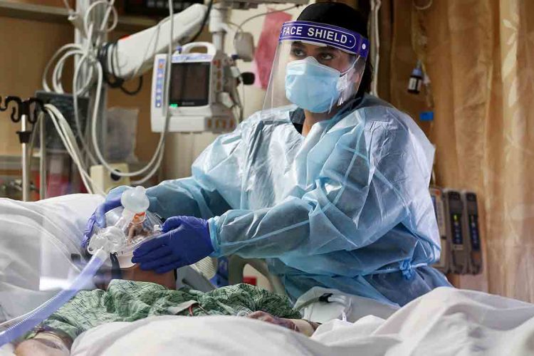 APPLE VALLEY, CALIFORNIA - DECEMBER 23:  (EDITORIAL USE ONLY) A clinician cares for a COVID-19 patient in the Intensive Care Unit (ICU) at Providence St. Mary Medical Center amid a surge in COVID-19 patients in Southern California on December 23, 2020 in Apple Valley, California. The 213 bed capacity hospital in San Bernardino County is currently treating at least 140 COVID 19-positive inpatients while operating at approximately 250 percent of ICU capacity. Southern California remains at zero percent of its ICU (Intensive Care Unit) bed capacity amid the spike in coronavirus cases and hospitalizations. (Photo by Mario Tama/Getty Images)