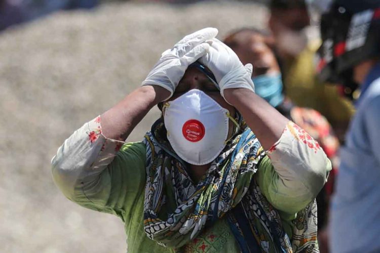 FILE- In this April 25, 2021, file photo, a relative of a person who died of COVID-19 reacts at a crematorium in Jammu, India. India’s death toll from COVID-19 has surpassed 200,000 as a virus surge sweeps the country, rooted in so-called super-spreader events that were allowed to happen in the months following the autumn when  the country had seemingly brought the pandemic under control. (AP Photo/Channi Anand, File)