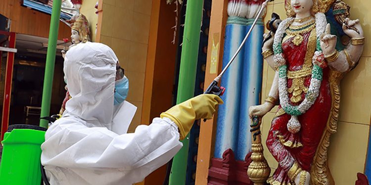 A member of the military wearing full protective gear sprays disinfectant at a Hindu temple to help curb the spread of the new coronavirus in Naypyitaw, Myanmar, Wednesday, April 1, 2020. The new coronavirus causes mild or moderate symptoms for most people, but for some, especially older adults and people with existing health problems, it can cause more severe illness or death. (AP Photo/Aung Shine Oo)