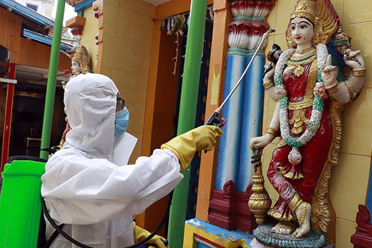 A member of the military wearing full protective gear sprays disinfectant at a Hindu temple to help curb the spread of the new coronavirus in Naypyitaw, Myanmar, Wednesday, April 1, 2020. The new coronavirus causes mild or moderate symptoms for most people, but for some, especially older adults and people with existing health problems, it can cause more severe illness or death. (AP Photo/Aung Shine Oo)
