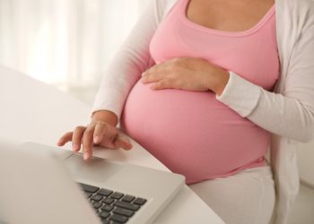Pregnant woman working on laptop at home