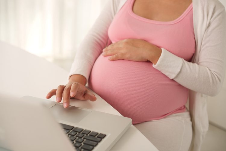 Pregnant woman working on laptop at home