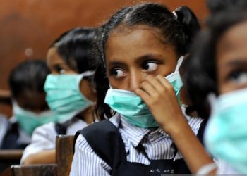Indian school children, wearing protective masks distributed by the local right wing Shiv Sena party for an awareness campaign, are seen in a classroom in Mumbai on August 10, 2009. The number of people to die from swine flu in India rose to six, health officials said, as the government called for calm and people flocked to public hospitals for tests. The latest to die of the (A)H1N1 virus were an ayurvedic or traditional medicine practitioner in Pune, 120 kilometres (75 miles) from India's financial hub Mumbai, and a four-year-old boy in the southern city of Chennai.  AFP PHOTO/ Pal PILLAI (Photo credit should read PAL PILLAI/AFP via Getty Images)