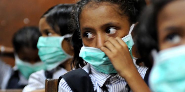 Indian school children, wearing protective masks distributed by the local right wing Shiv Sena party for an awareness campaign, are seen in a classroom in Mumbai on August 10, 2009. The number of people to die from swine flu in India rose to six, health officials said, as the government called for calm and people flocked to public hospitals for tests. The latest to die of the (A)H1N1 virus were an ayurvedic or traditional medicine practitioner in Pune, 120 kilometres (75 miles) from India's financial hub Mumbai, and a four-year-old boy in the southern city of Chennai.  AFP PHOTO/ Pal PILLAI (Photo credit should read PAL PILLAI/AFP via Getty Images)