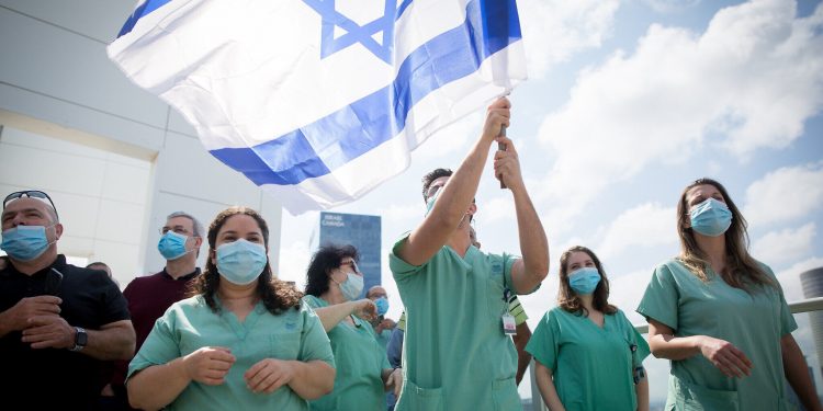Israeli medical staff cheer an Israeli airforce acrobatic team flying over Ichilov hospital in Tel Aviv on Israel's 72nd Inependence Day. This year, the airforce will fly over all the hospitals in Israel as a way of honouring the medical staff during the Coronavirus outbreak. April 29, 2020.  Photo by Miriam Alster/Flash90 *** Local Caption *** יום העצמאות
מטס
תל אביב
איכילוב
קורונה
מטוסים
תל אביב
דגלים
דגל ישראל