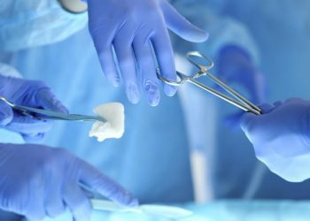 Surgeons hands holding and passing surgical instrument to other doctor while operating patient. Resuscitation medicine team holding steel medical tools saving patient. Surgery and emergency concept