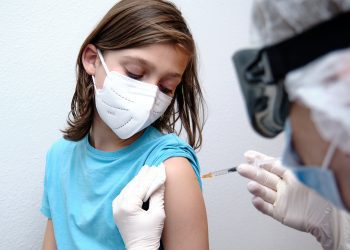 Female doctor giving covid-19 vaccine to a boy