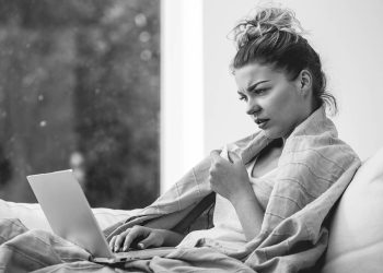 Young ill woman in bed with laptop