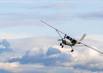 Propeller plane flying on the cloudy sky background