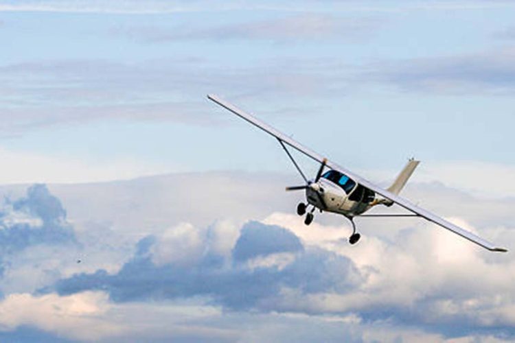 Propeller plane flying on the cloudy sky background
