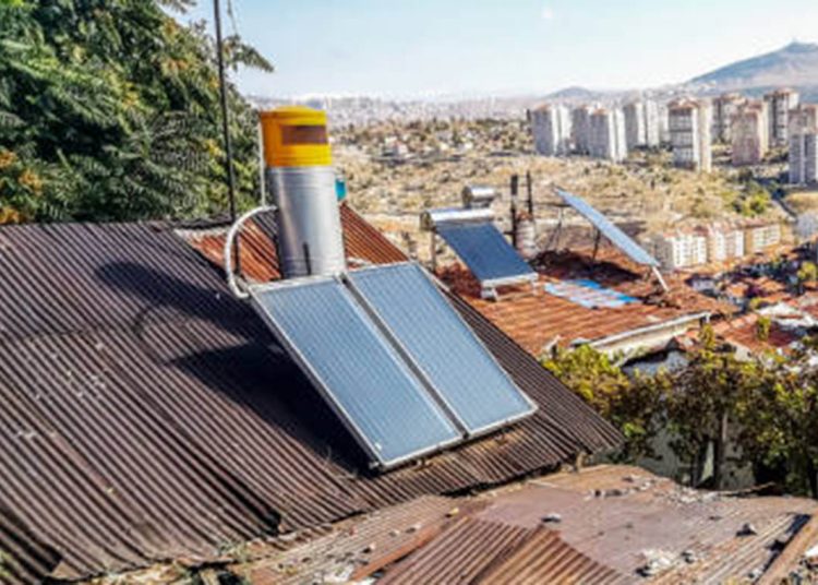 Solar panels and satellite dishes are installed on ancient tiled roofs in the slums of Ankara, Turkey. Garbage and old roofs of huts against the background of a panorama of a modern Turkish city