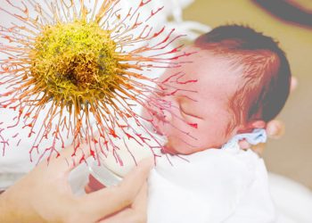 Newborn Baby drinking milk from glass cup.