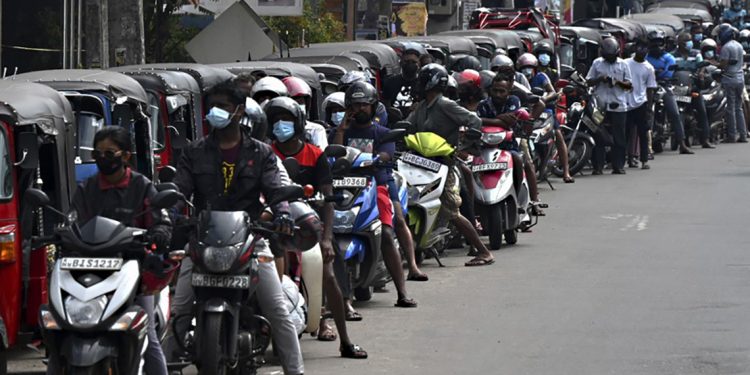 Motorbikes and three-wheeler vehicles queue to fill their tanks up at a Ceylon Petroleum Corporation fuel station in Colombo on April 12, 2022. - Crisis-stricken Sri Lanka defaulted on its $51 billion external debt on April 12 after running out of dollars to import desperately needed goods and sparking widespread protests demanding the president's resignation. (Photo by Ishara S. KODIKARA / AFP)