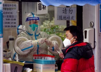epa10365069 A man takes Coronavirus PCR test in the street testing booth, in Shanghai, China, 14 December 2022. China will no longer report asymptomatic cases of Covid-19 in its daily report, according to the National Health Commission announcement on 14 December. With easing Covid-19 restrictions, a rising number of infections is circulating in Shanghai. This year the holiday season is decorated with people staying at home recovering from the virus. Shopping malls and restaurants are mostly empty, while people can be seen on the streets in the morning before and in the evening after work.  EPA-EFE/ALEX PLAVEVSKI