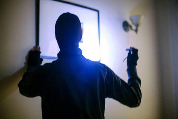 Unrecognizable male burglar stealing an artwork.