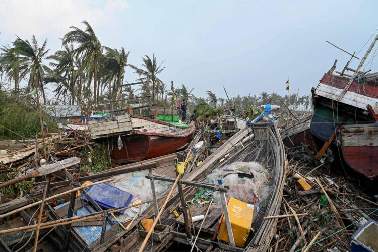 TOPSHOT - Local residents stand on broken boats in Sittwe, on May 15, 2023, after cyclone Mocha made a landfall. Cyclone Mocha made landfall between Cox's Bazar in Bangladesh and Myanmar's Sittwe carrying winds of up to 195 kilometres (120 miles) per hour, the biggest storm to hit the Bay of Bengal in more than a decade. (Photo by Sai Aung MAIN / AFP)