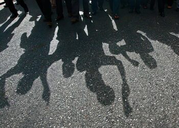 Protesters cast a shadow as they march on a street