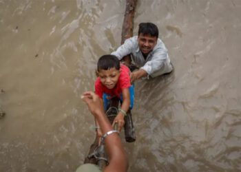නවදිල්ලියේ යමුනා ගඟේ ජල මට්ටම ඉහළ යාමෙන් අවතැන් වීමෙන් පසු ඉදිවෙමින් පවතින ගුවන් පාලමකට නැගීමට පියකු තම පුතාට උදව් කරන අයුරු [අඩ්නාන් අබිඩි/රොයිටර්]