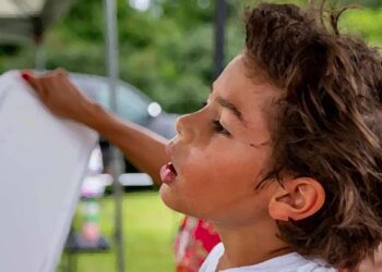 A cute young boy relaxes while he sweats on a hot summer day.