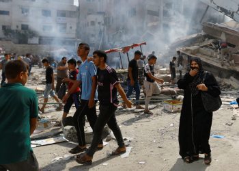Palestinians walk near the rubbles in the aftermath of Israeli strikes, in Khan Younis, southern Gaza Strip October 10, 2023. REUTERS/Ibraheem Abu Mustafa