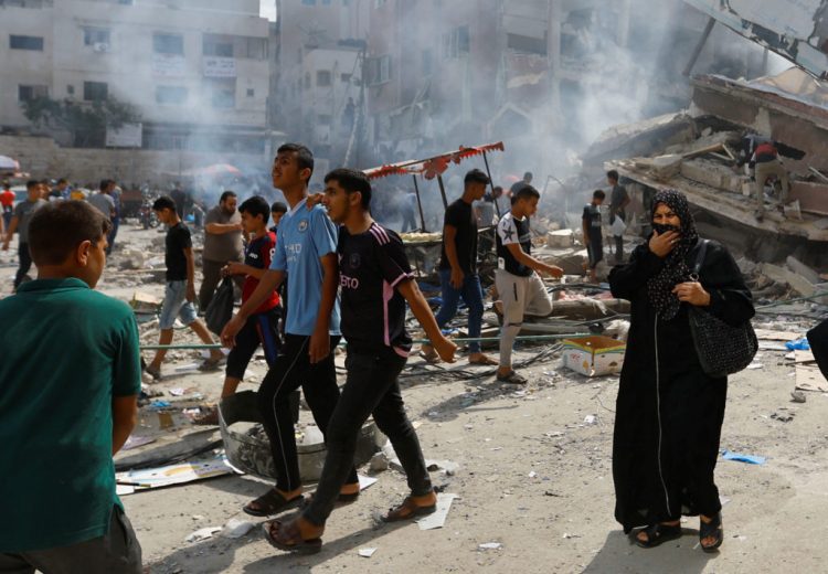 Palestinians walk near the rubbles in the aftermath of Israeli strikes, in Khan Younis, southern Gaza Strip October 10, 2023. REUTERS/Ibraheem Abu Mustafa