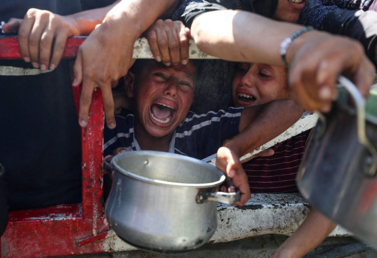 Palestinians wait to receive food from a charity kitchen, amid a hunger crisis, in Gaza City, July 23, 2025. REUTERS/Mahmoud Issa     TPX IMAGES OF THE DAY